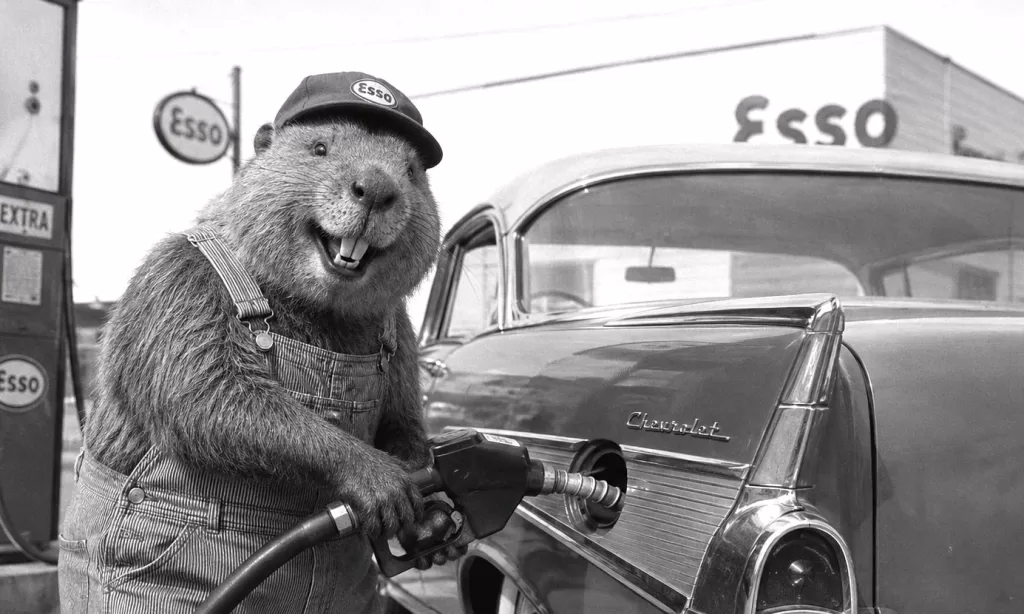 Photorealistic black-and-white 1950s scene of a smiling beaver wearing striped bib overalls and a baseball cap while pumping gas into a classic 1957 Chevrolet at a vintage service station.